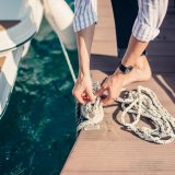 Man tying rope of a boat onto pier